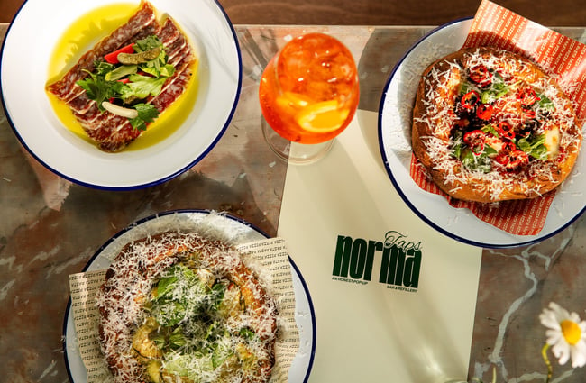 Three meals on a table next to a Norma Taps menu.