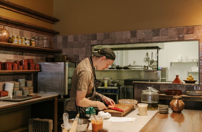 A chef slicing a piece of fish inside the open kitchen.