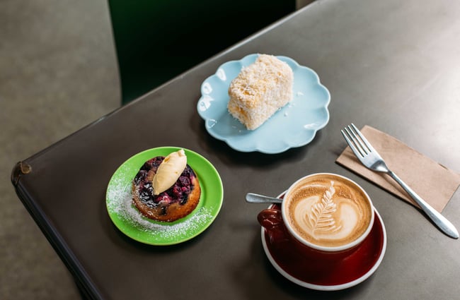 A close up of a coffee and cakes on a table.