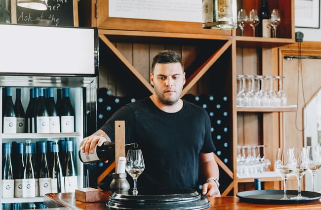 A man pouring wine behind the counter at Pegasus Bay winery and restaurant in North Canterbury.