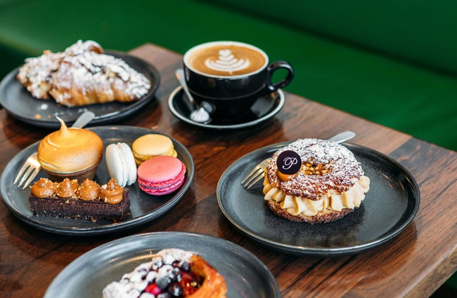 A Paris brest, macarons, intricate tarts and pastries and a coffee on a table at Pembroke Pâtisserie.