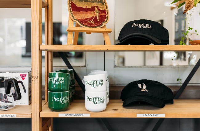 Mugs and caps on shelves inside Peoples Coffee Roastery.
