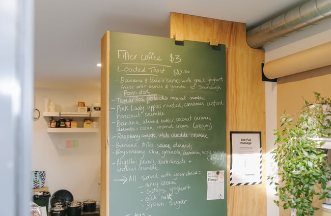 Green menu chalkboard on the wall at Posh Porridge.