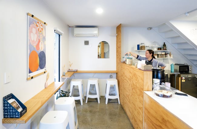 A view of the kitchen and dining area inside a small cafe space.