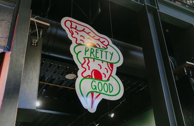 Green and red Pretty Good Pizza logo sticker on the front window.