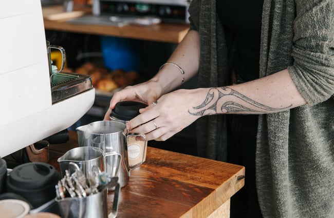 Barista putting a lid on reusable coffee cup.
