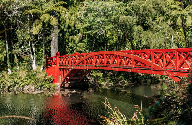 A red bridge across a pond.