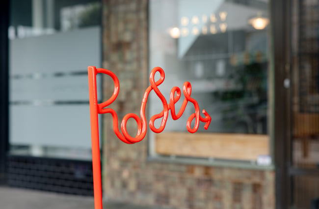 A close up of a red sign that says 'Roses'.