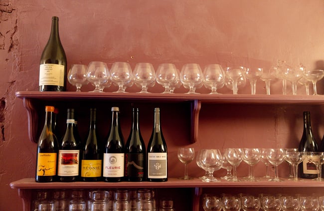 Wine bottles and wine glasses lined up on floating shelves.