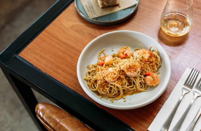 A plate of prawn pasta on a wooden table at Sazio.
