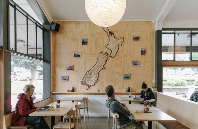 Seating area with wooden map of New Zealand on the wall at Scroggin, Wānaka.