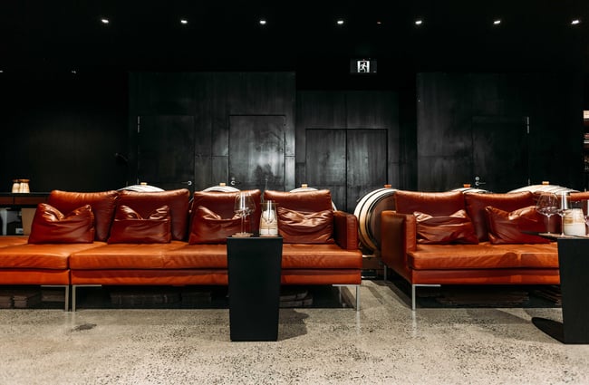 Brown leather couches sitting in a room painted black.