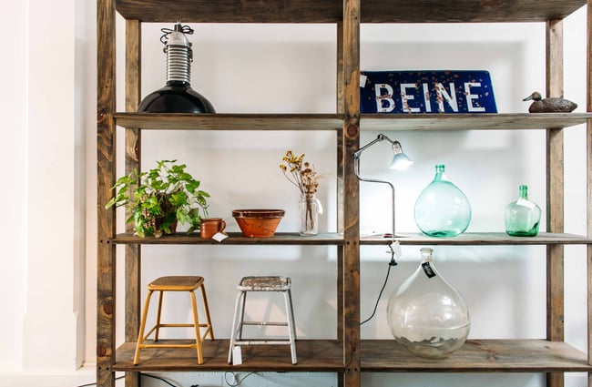 Glasses, pot plants and homewares on wooden shelves.