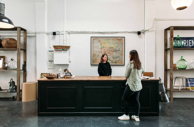 A customer talking to a staff member behind a large black counter inside So Vintage.