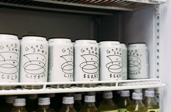 A close up of cans of beer behind a glass fridge.