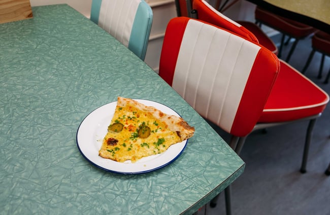 A delicious looking slice of pizza on a retro table.