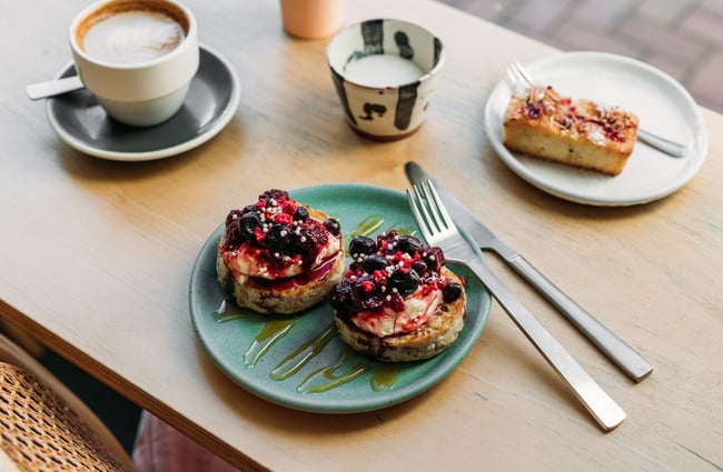 A close up of blueberry compote on crumpets on a wooden bench table.