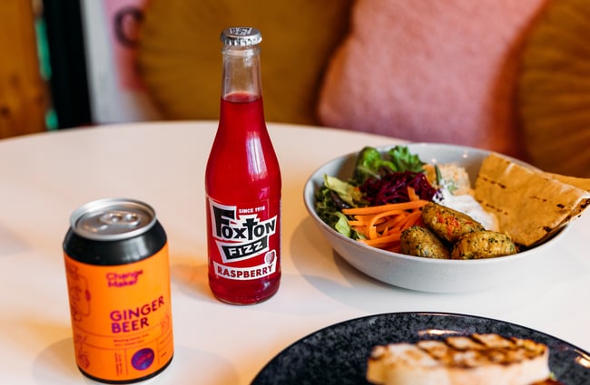 Fizzy drinks and a falafel bowl on a table.
