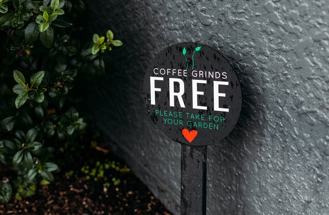 A close up of a 'free coffee grinds' sign.
