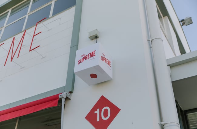 A small 'Supreme' sign attached the outside of a cafe.