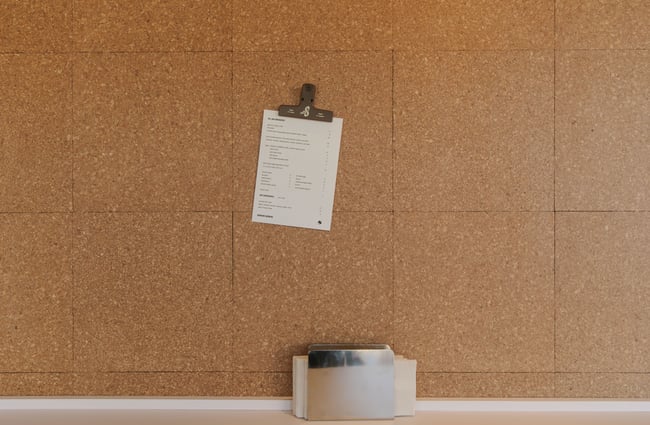 A menu tacked to a cork wall.
