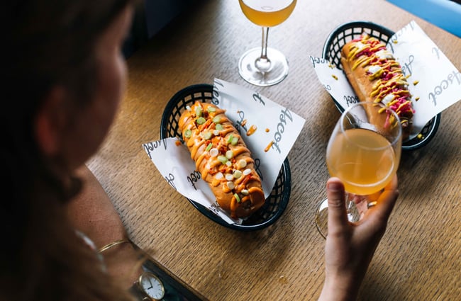 Hotdogs and wine on a table.