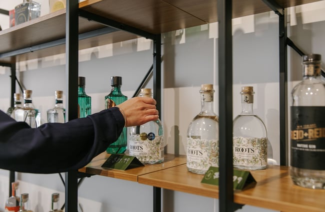 Hand picking a bottle of gin of a shelf at The Juniper Collective, Christchurch.