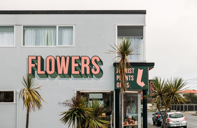 A huge 'Flowers' sign painted on a grey building.