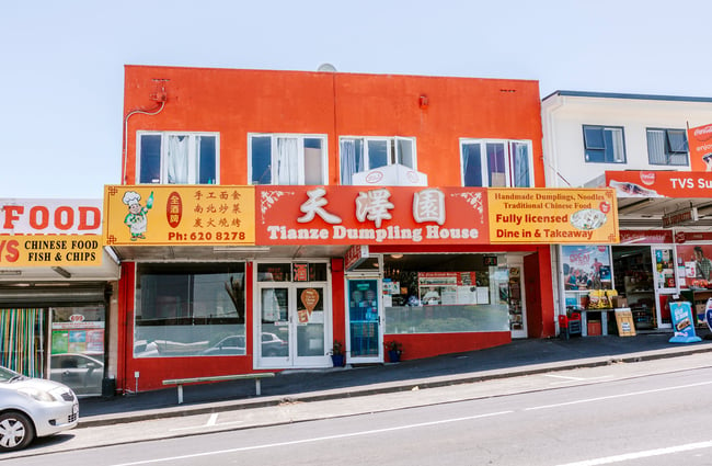 The bright orange exterior of a dumpling house on a sunny day.