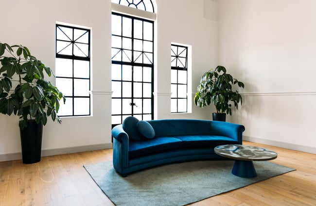 A large bright blue couch in a brightly lit foyer.