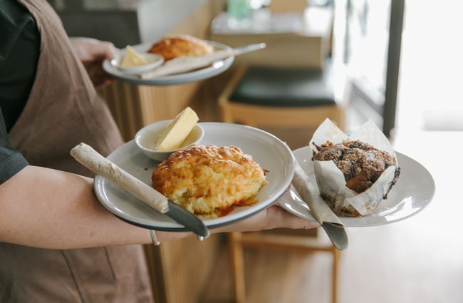 Person holding plates of muffins and cheese scones at Truffle café, Christchurch.