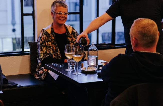 A man pouring a glass of wine at a table.