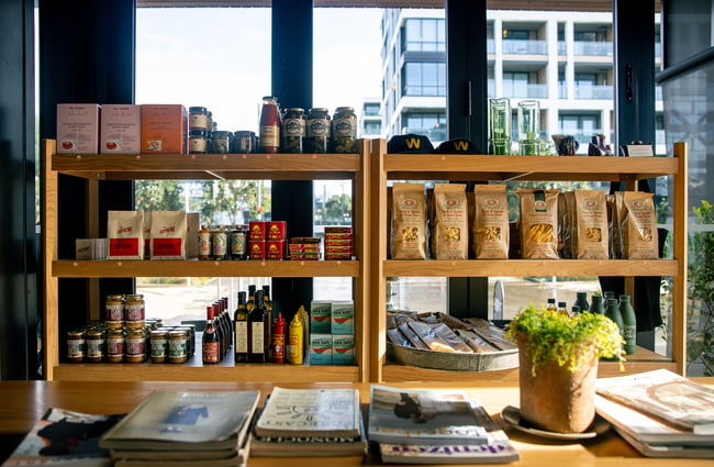 A view of the coffee and pantry goods available for sale on wooden shelves.