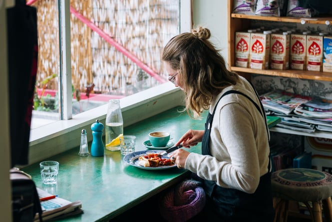 A woman eating at a counter by the window inside Gispy Kitchen cafe Wellington.