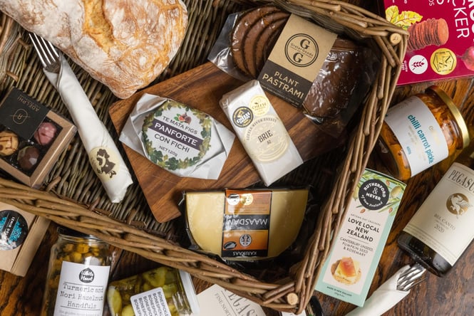 A flatlay of cheese and spreads in a basket.