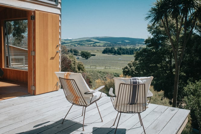 Two wired deck chairs with cushions on a wooden porch at Christchurch accommodation.