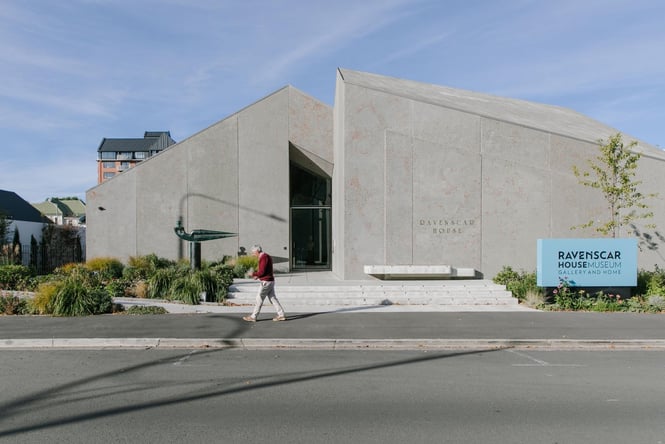 A person walking down the street past the concreted building the Ravenscar house.