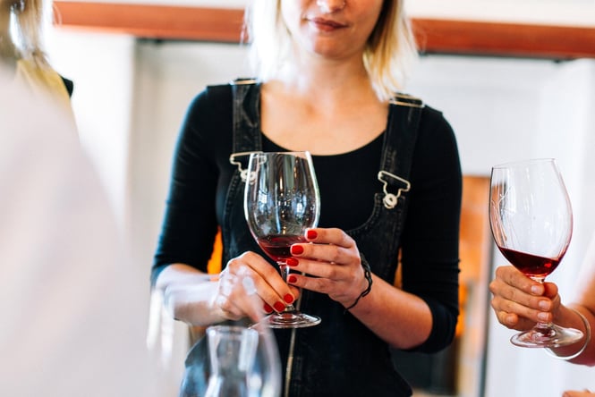 A woman holding a glass of red in two hands.