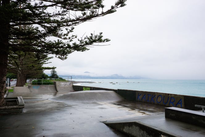 A skate park right next to the ocean on a grey and wet day.