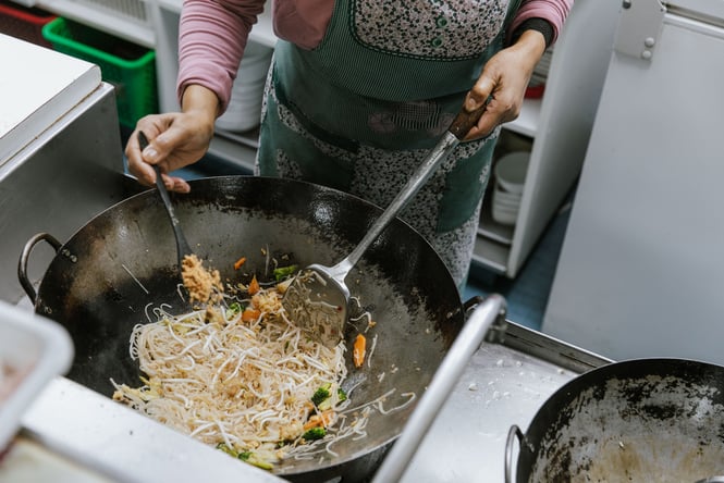 Noodles being cooked in a wok.