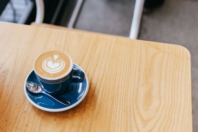 A flat white in a blue cup on a table.