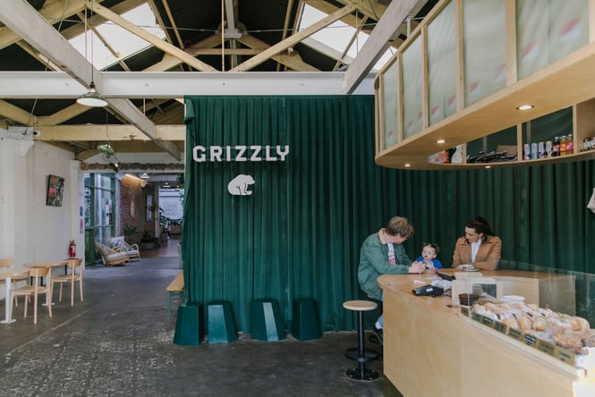A family sitting at the bench at Grizzly Baked Goods with a big green velvet backdrop.