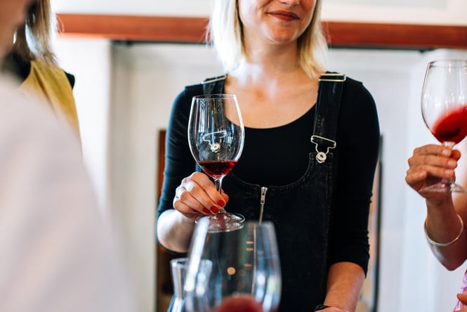 A woman holding a glass of red wine.
