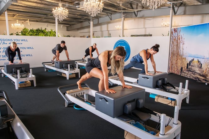 Men and women working the reformer machines at Core Pilates and Mind.