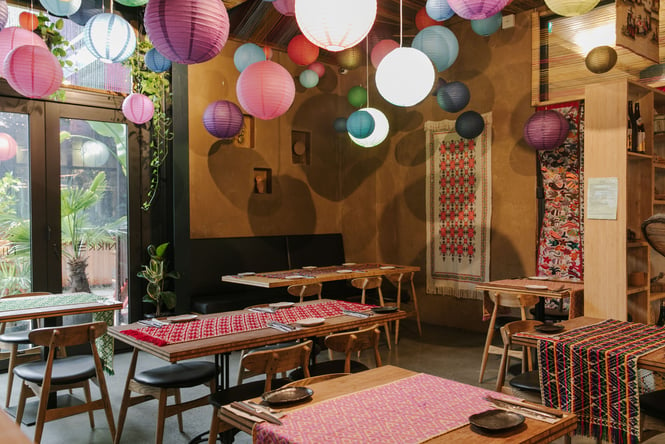 Colourful paper lampshades hanging from the ceiling inside a restaurant.