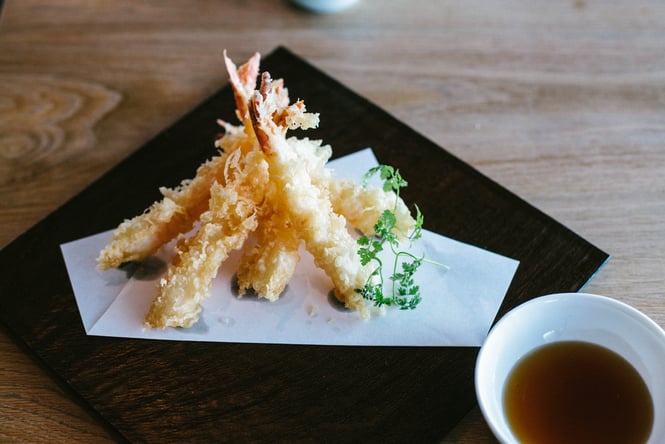 Seafood tempura on a black plate.