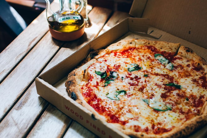 A close up of a margherita pizza on a wooden table.