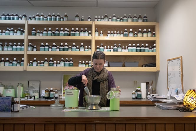 A woman measuring out herbs at a counter.