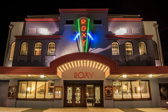 The brightly lit exterior of Roxy Cinema at night.
