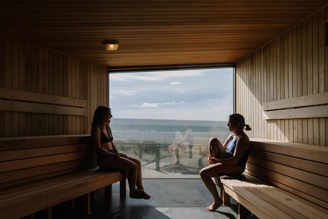 Two women enjoying a conversation while in the sauna looking over the beach.